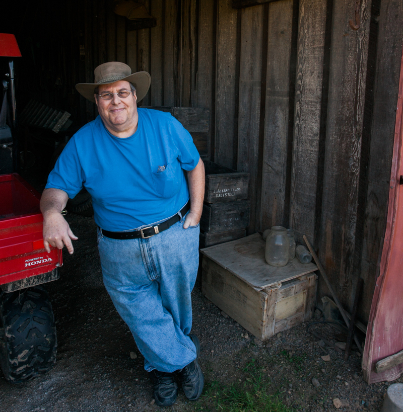 Jim Frediani standing in a barn leaning on a tractor